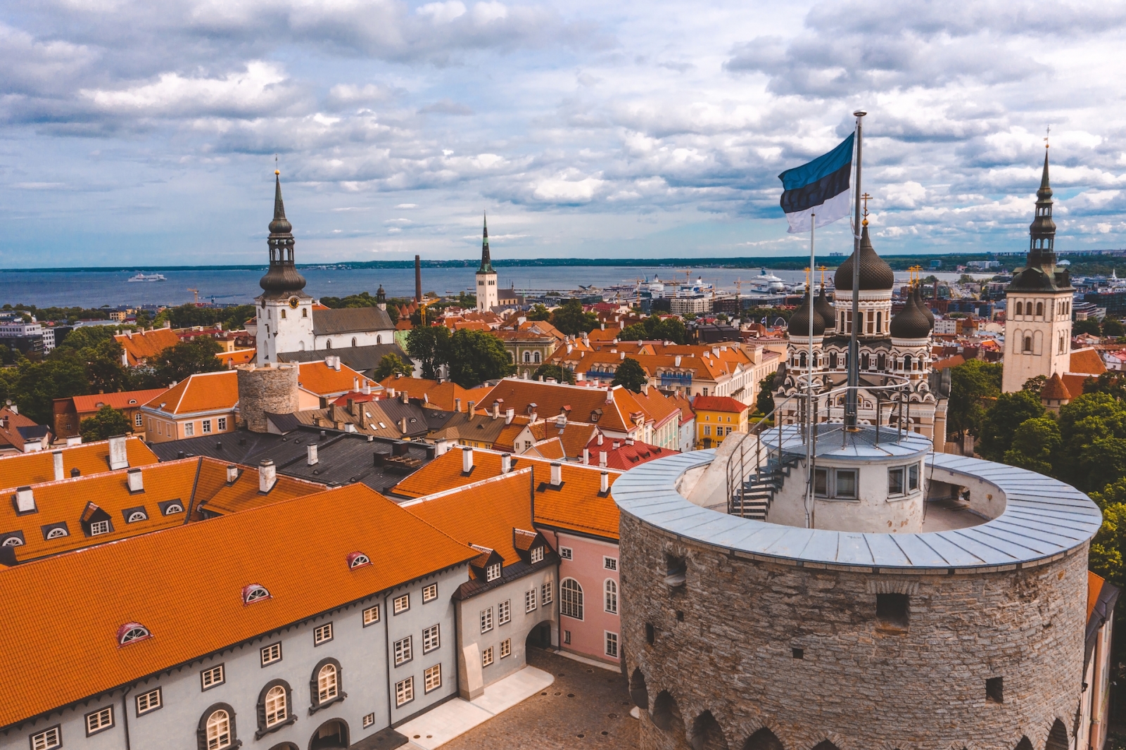 Vista ravvicinata della bandiera estone in cima alla vecchia torre medievale.