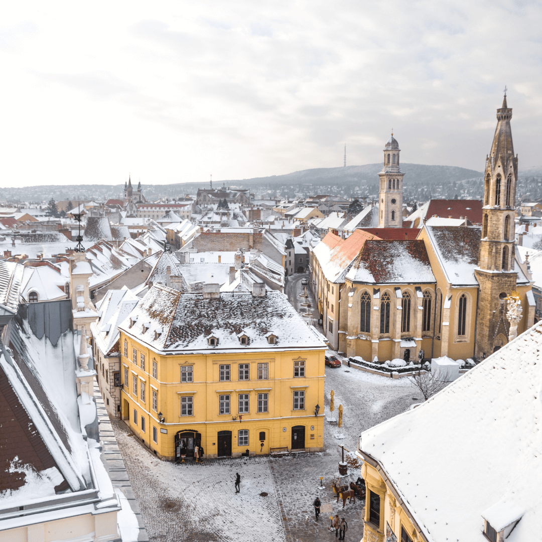 Città vecchia di Sopron in inverno_ edifici storici tra cui la chiesa gotica della Capra nel centro della città coperta di neve