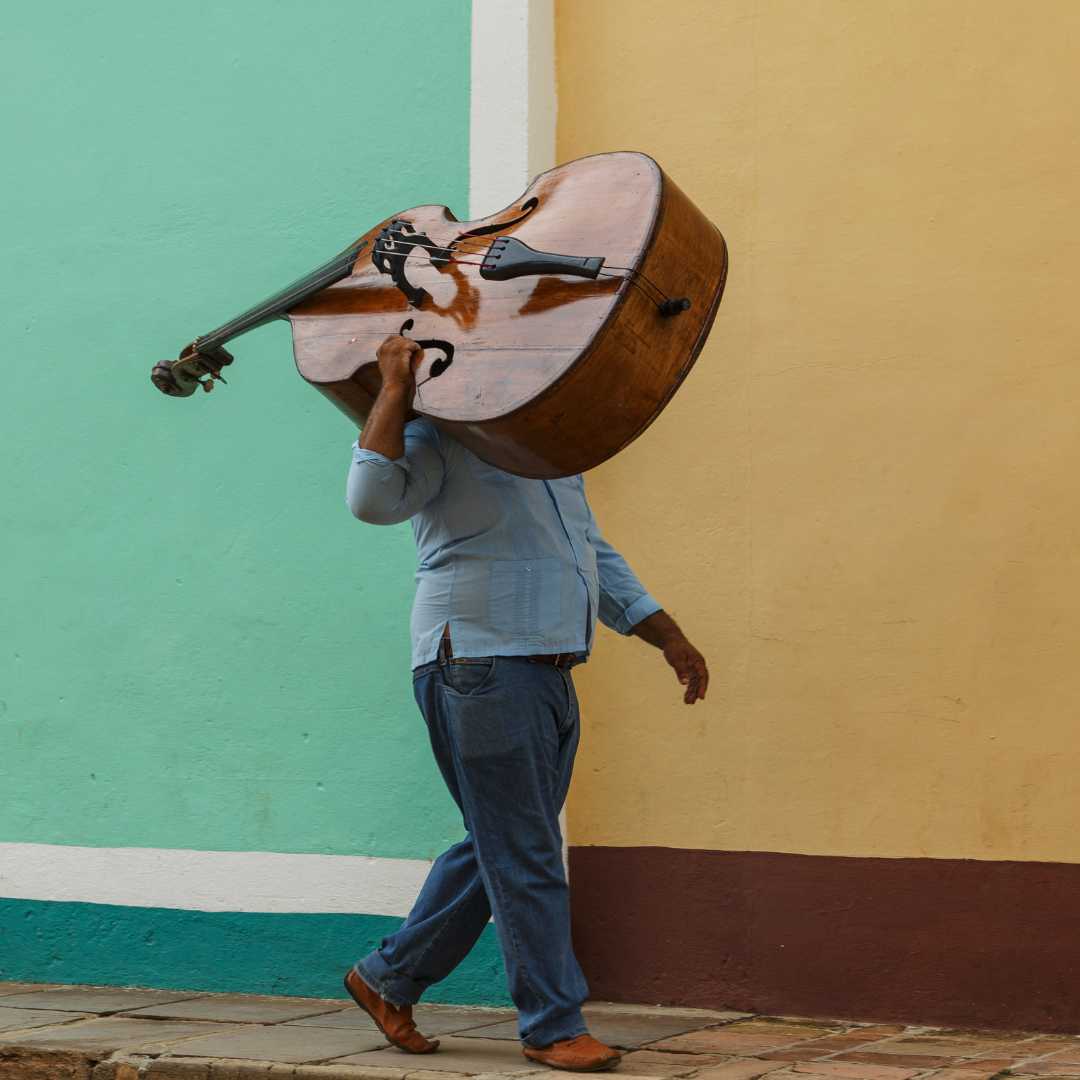Homme cubain portant une contrebasse, allant au travail