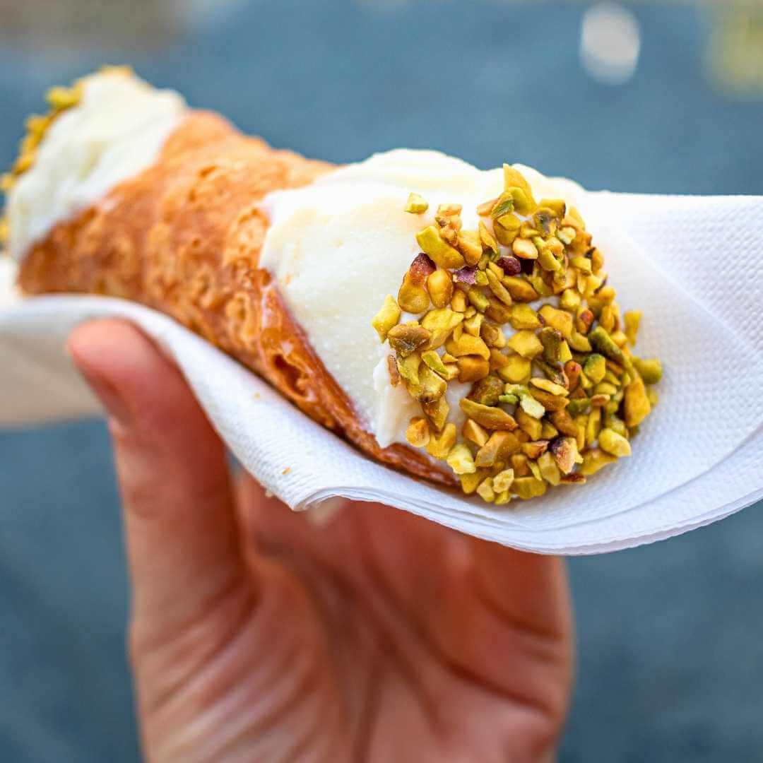 Un cannolo tradizionale con la guarnizione al pistacchio