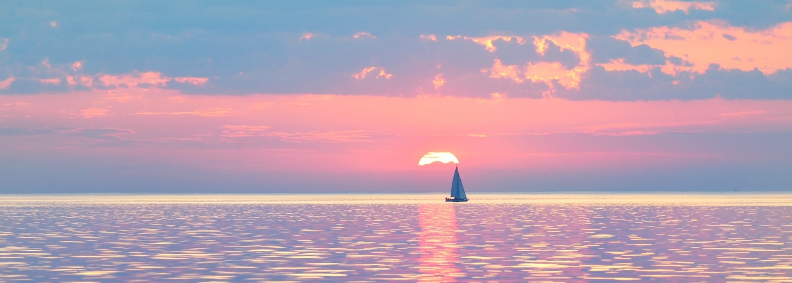 Sloop rigged yacht sailing in an open Baltic sea at sunset