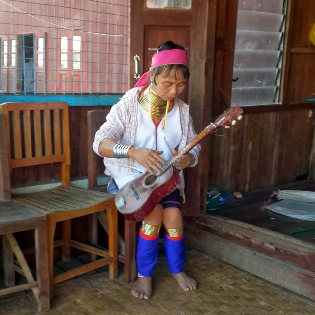 Женщина с длинной шеей в Бирме на озере Инле играет на гитаре