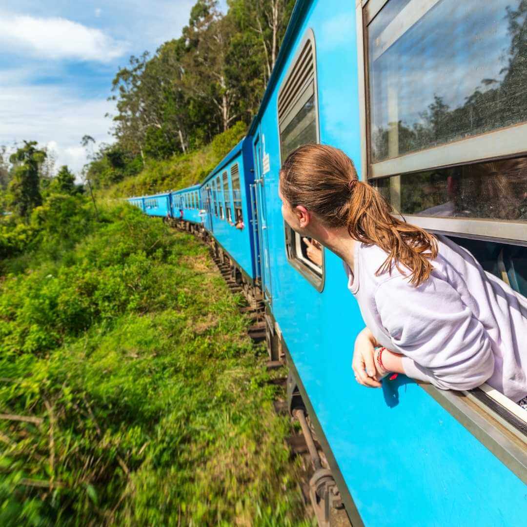 A young woman enjoyes the train ride from Ella to Kandy among tea plantations in the highlands of Sri Lanka