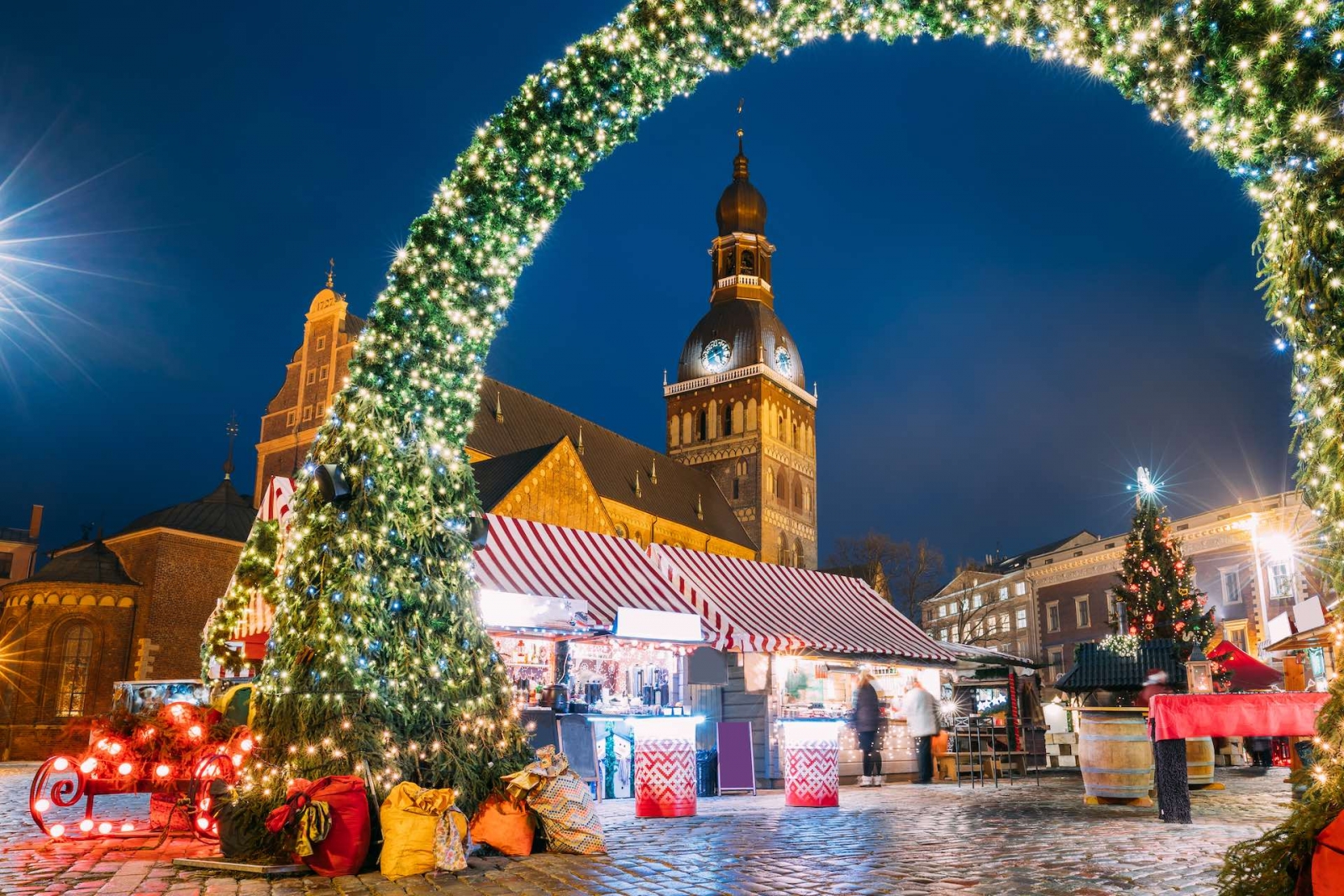 Рига, Латвия.  Рождественская ярмарка на Домской площади с Рижским Домским собором.  Рождественская елка и торговые дома