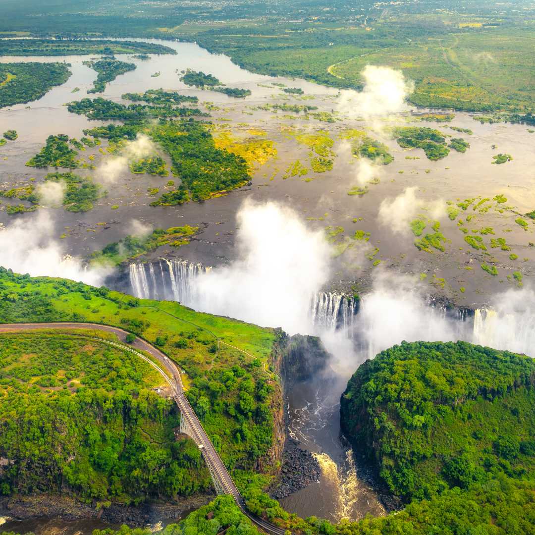 Cascate Vittoria nello Zimbabwe e nello Zambia, foto aerea in elicottero, foresta verde intorno alle maestose cascate dell'Africa. Livingston Bridge sopra il fiume