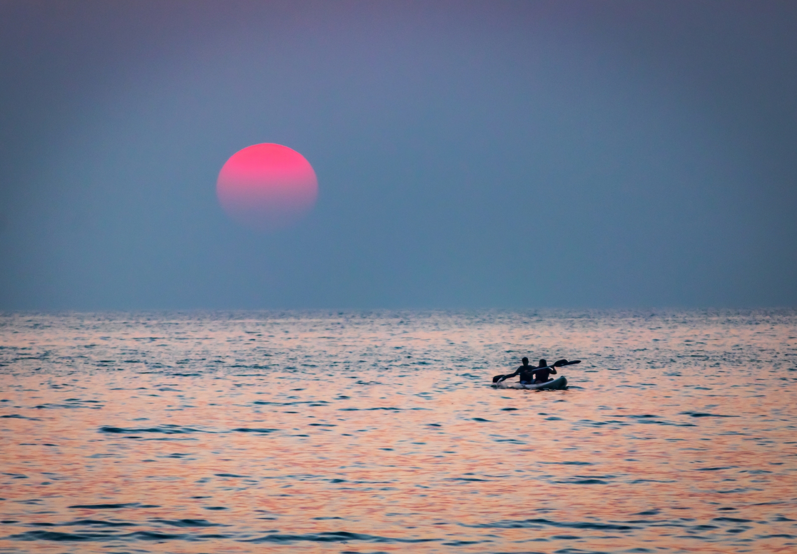 Pareja navegando en kayak con remos en la playa/mar durante la puesta de sol en la hermosa ubicación de la playa de Palolem, Goa, India