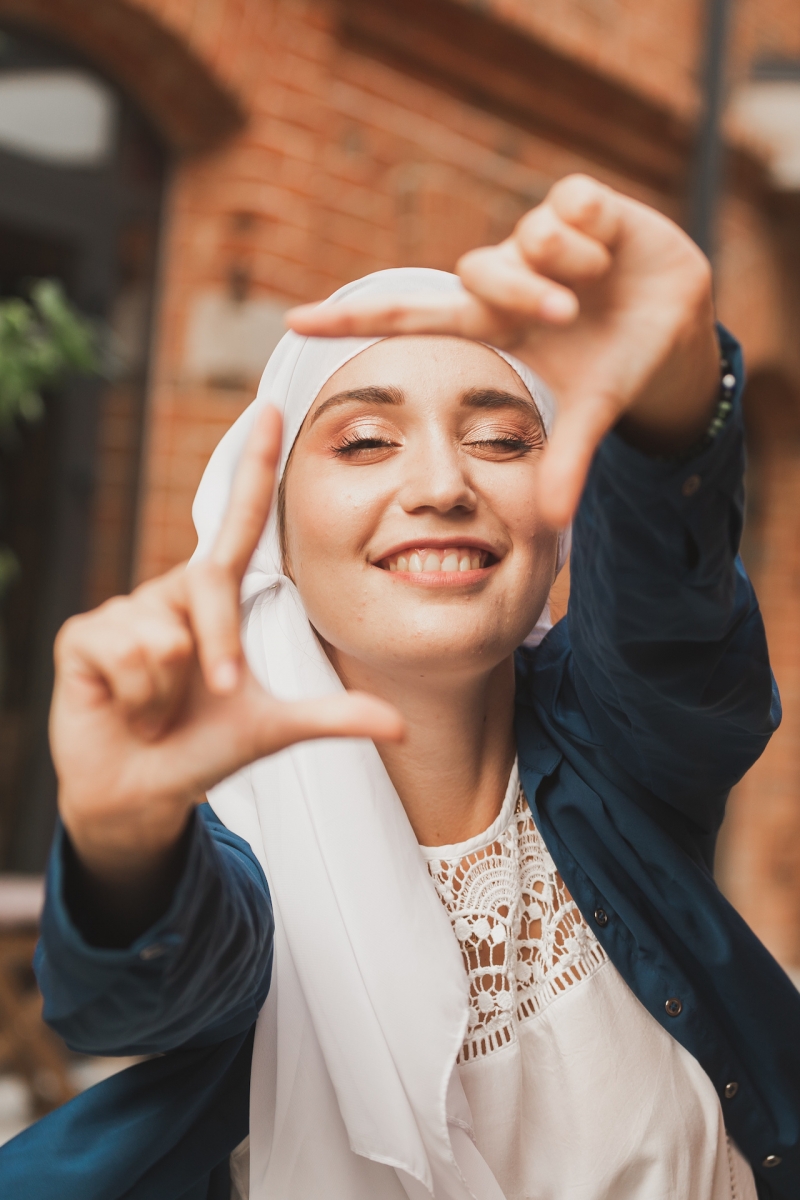 Портрет молодой мусульманской девушки, делающей кадр камеры пальцами на открытом воздухе