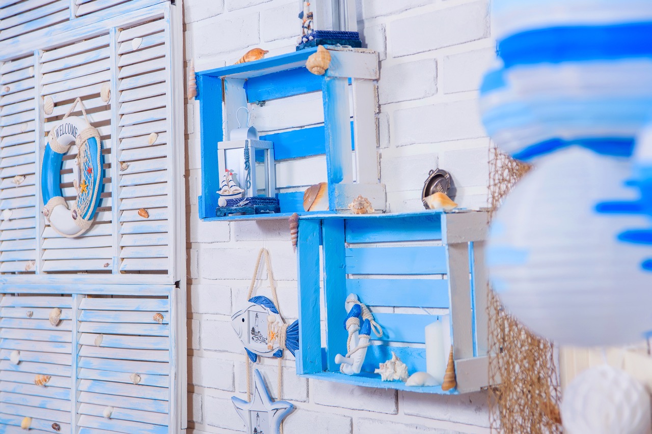 White brick wall. The interior of the room. Decor in marine style. Shelves of wooden boxes. Wooden shutter.