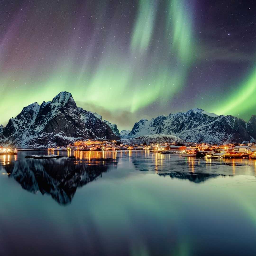 Aurora boreale che balla su una montagna in un villaggio di pescatori a Reine, Lofoten, Norvegia