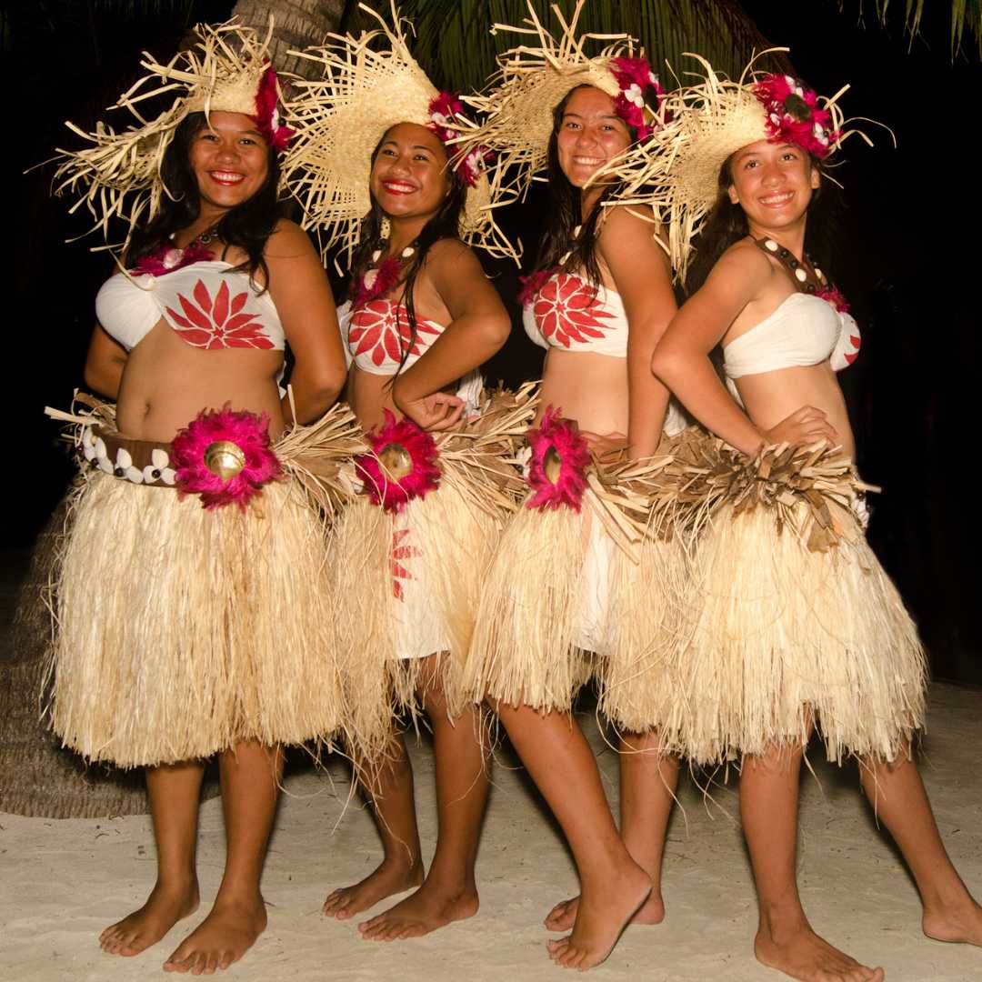 Portrait of young Polynesian Pacific Island Tahitian women dancers in colorful costume dancing on tropical beach