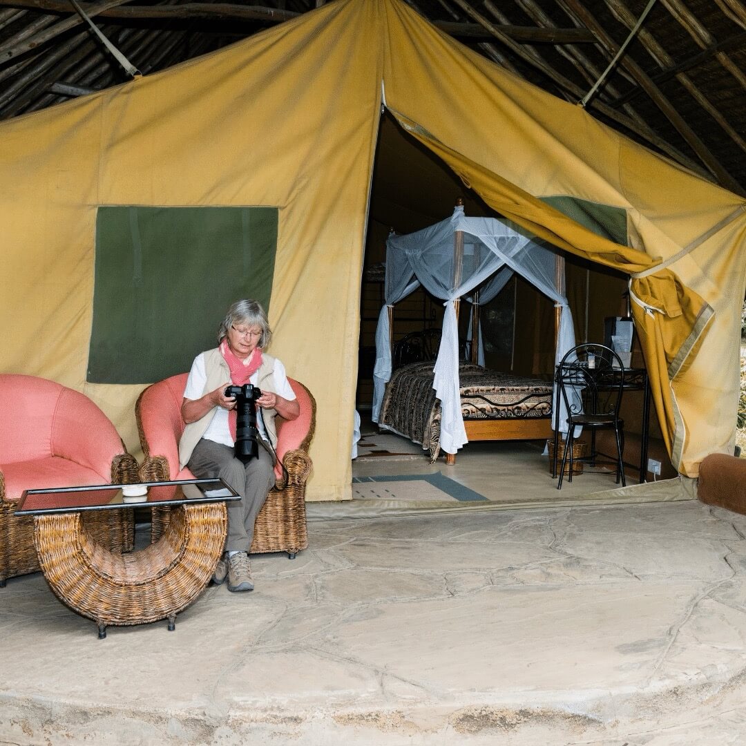 Donna con la macchina fotografica al campo safari sotto la confortevole tenda in Kenya, Africa