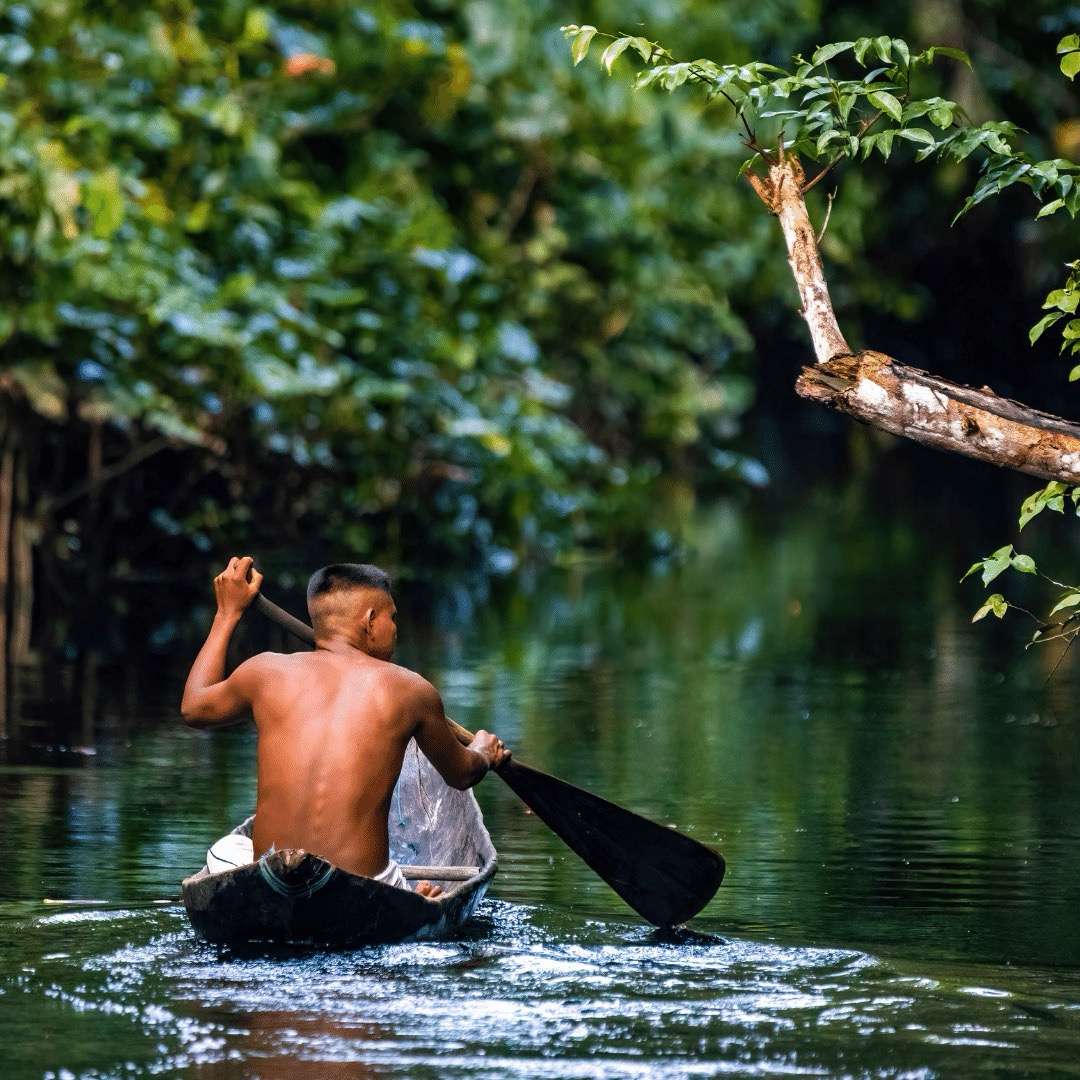 Native Tribal Man in Amazonia Rainforest in Handmade Boat, Peru