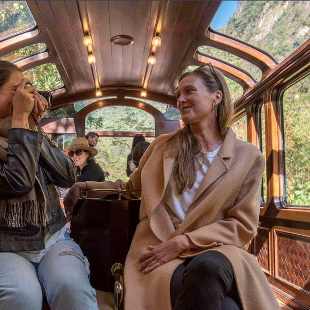 Dos amigas disfrutan del viaje y ven a través de las ventanas panorámicas del Tren Explorador Andino