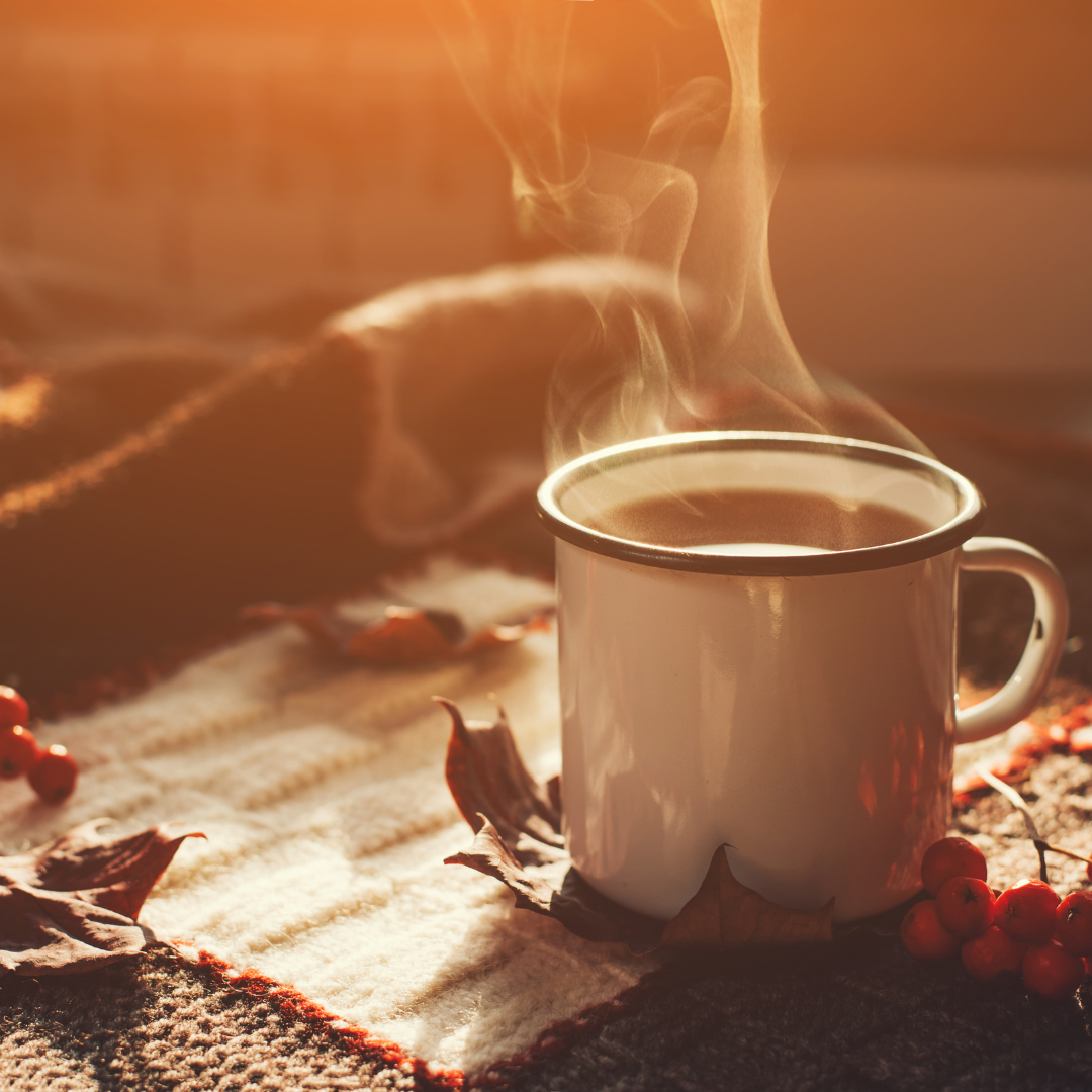 Heiße, dampfende Tasse Kaffee und Gewürze auf einem warmen Plaid an einem strahlend sonnigen Tag