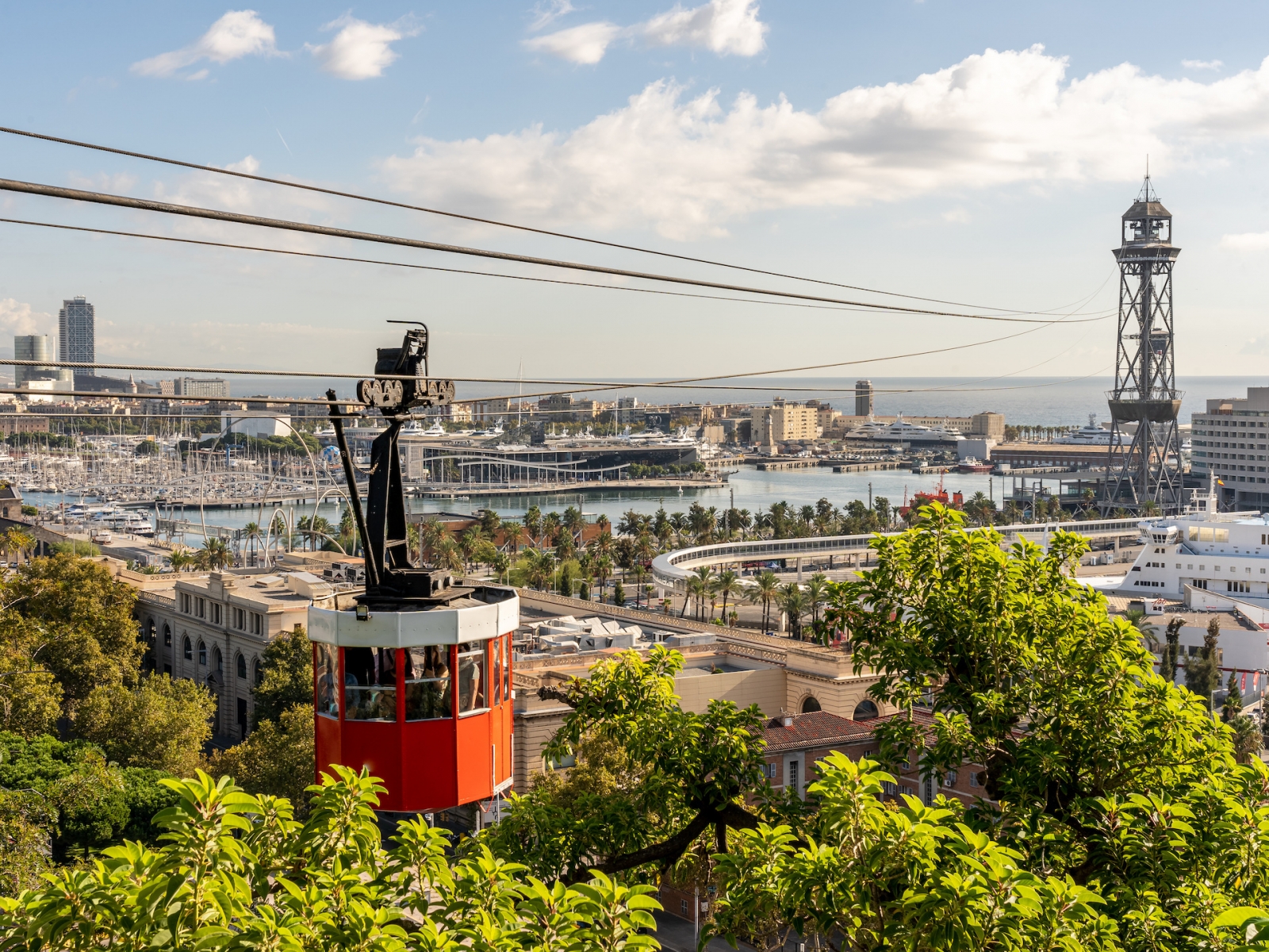 историческая красная кабина канатной дороги с гаванью и панорамой города Барселоны, Испании