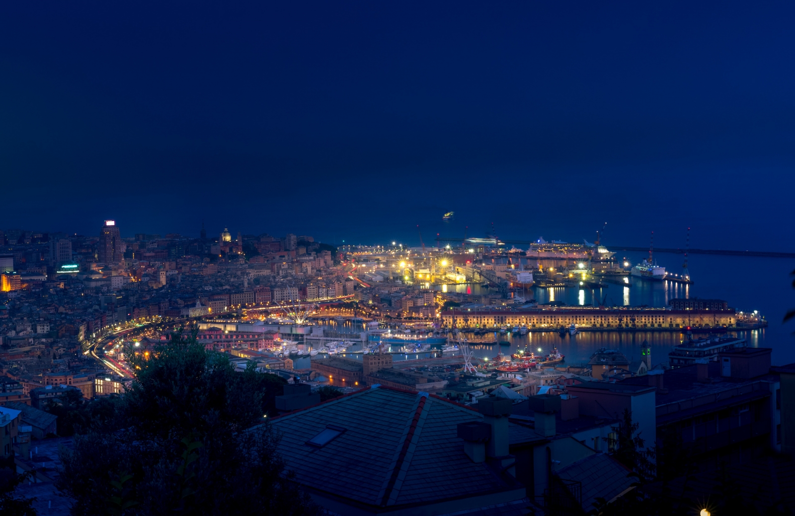 Paysage urbain nocturne de Gênes avec le vieux port, les navires de croisière, les grues maritimes et portuaires en arrière-plan