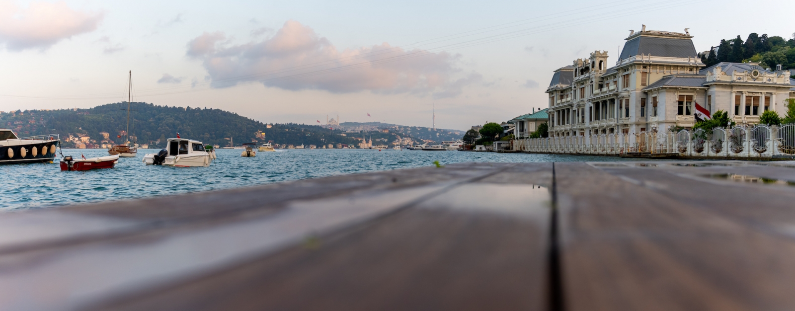 Вид на Босфор, лодки, скамейку во дворе и исторические особняки с пляжа.  Пляж Бебек.  Бешикташ Стамбул Турция