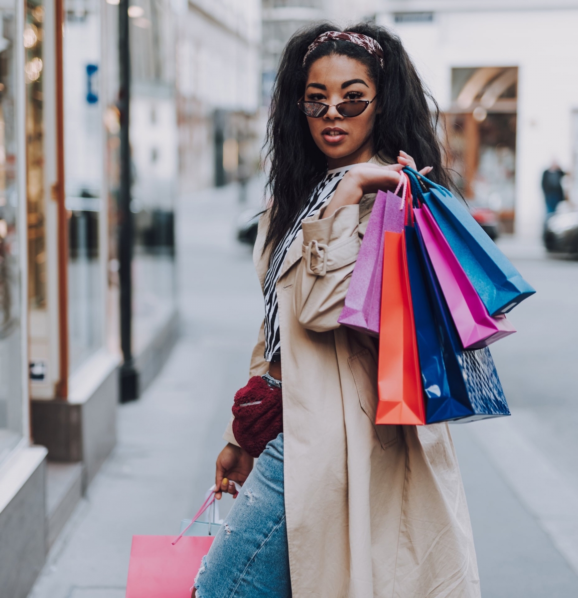 Attraktive afroamerikanische Frau mit Einkaufstüten steht auf der Straße