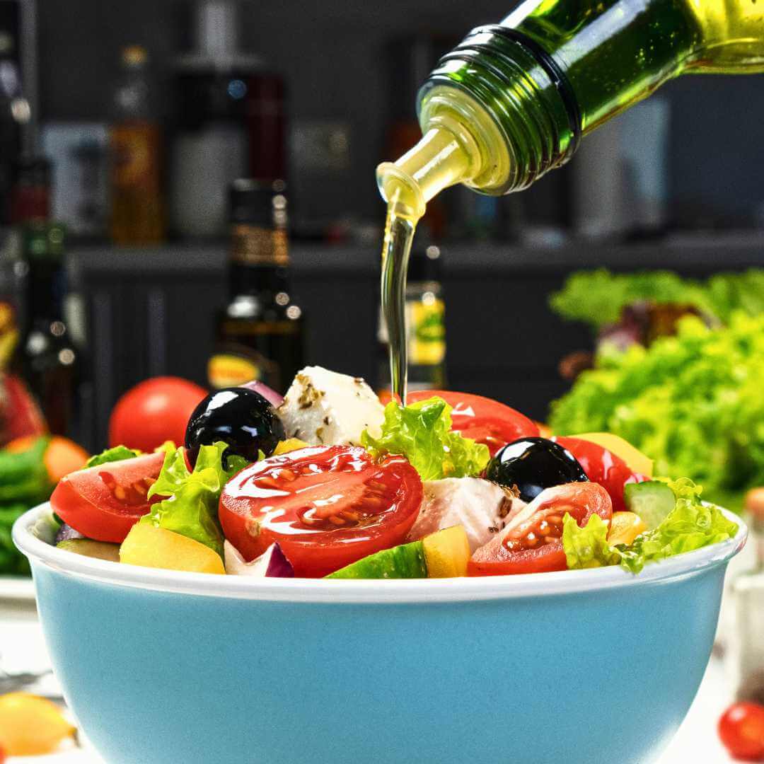 Versare l'olio d'oliva sull'insalata greca di verdure fresche