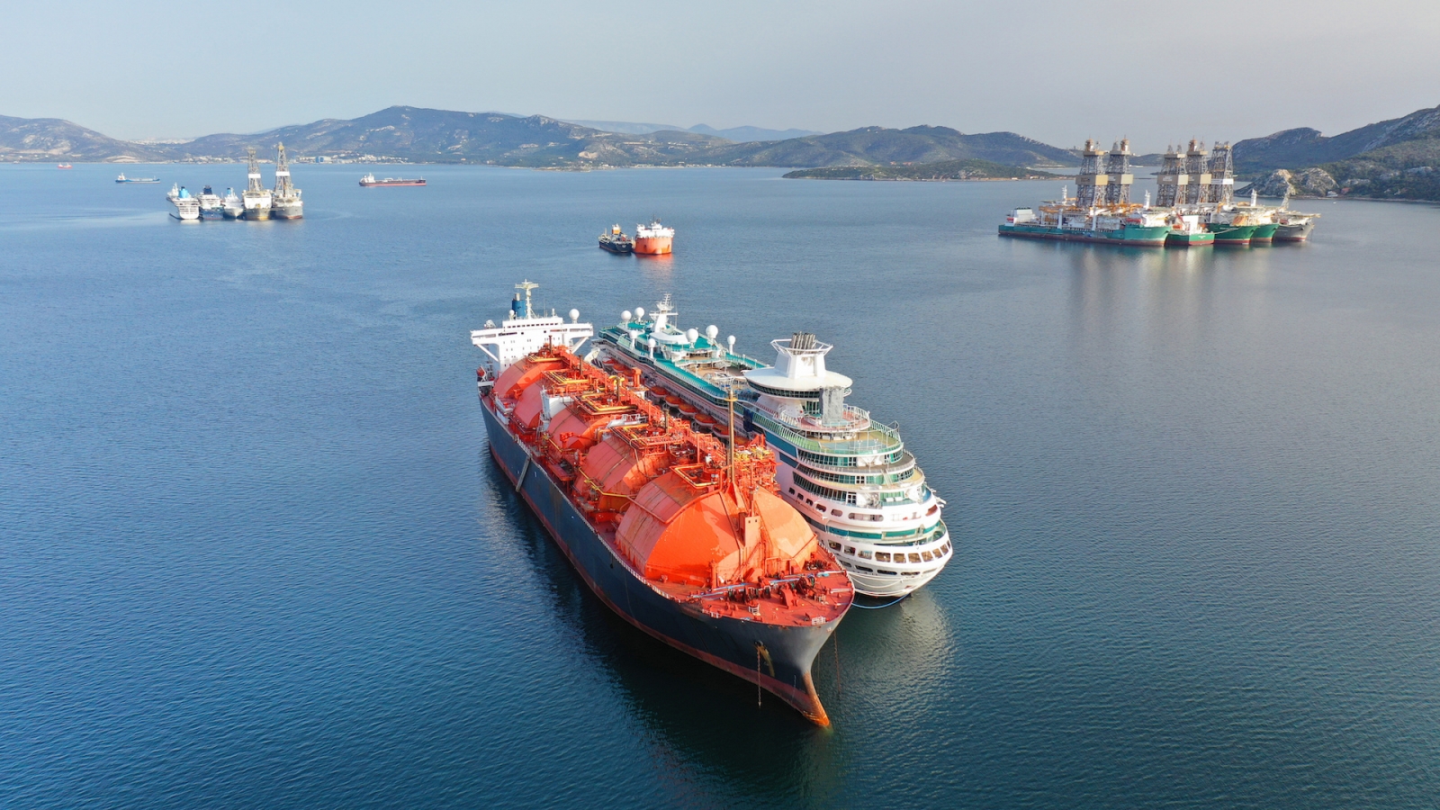 Foto aérea de un dron de un petrolero de GNL abandonado y un pequeño crucero anclado en una zona industrial