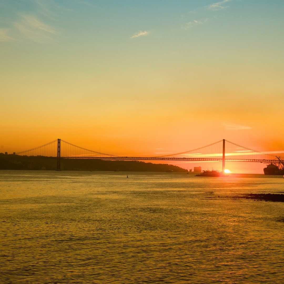 Blick auf die Brücke 25 de Abril in Lissabon, Portugal, bei Sonnenuntergang