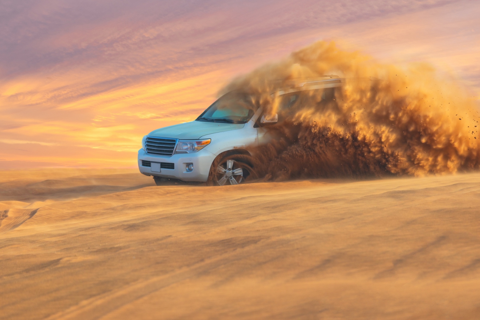 Aventure hors route avec SUV dans le désert d'Arabie au coucher du soleil.