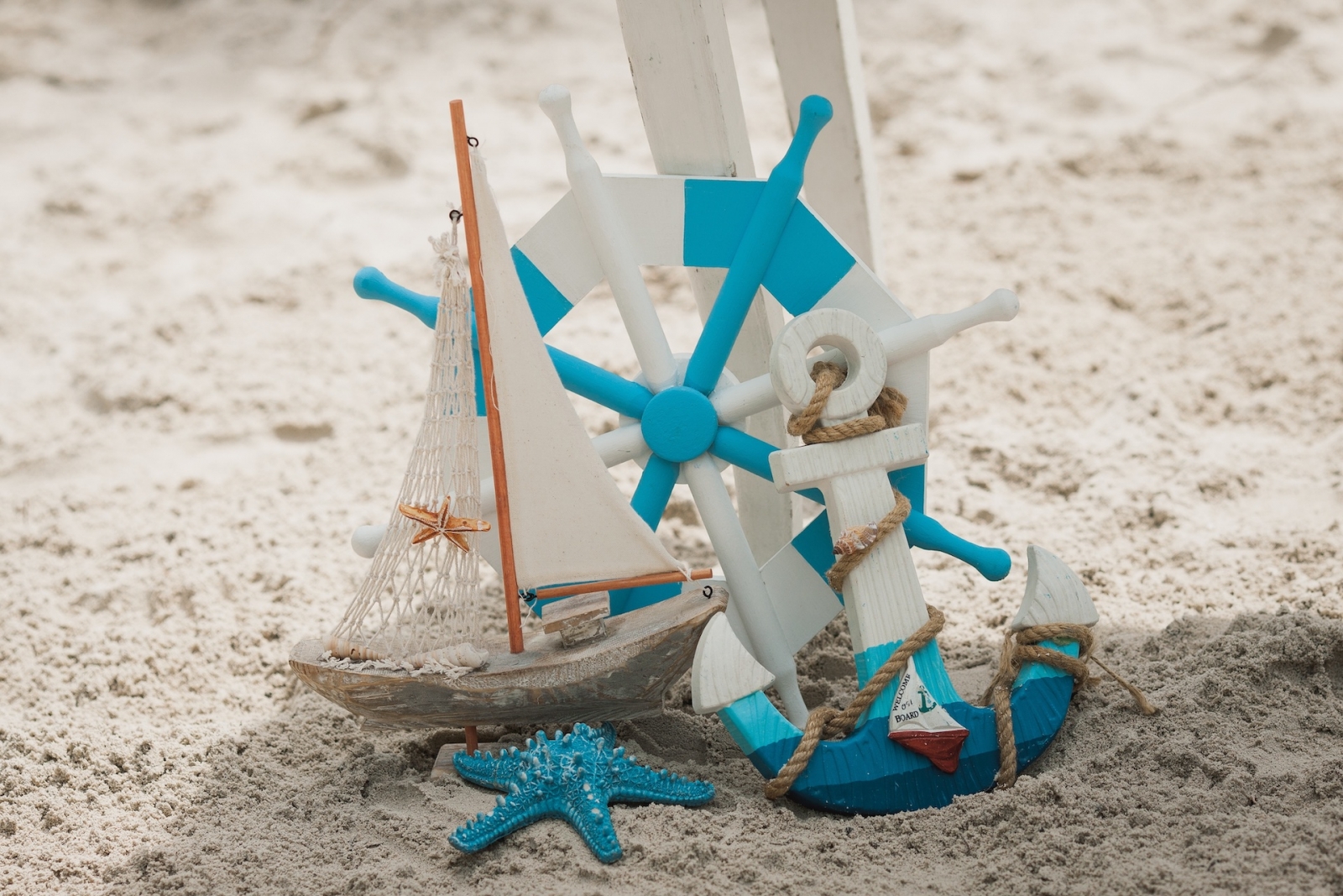 Kleines blau-weißes Schiff und Anker an einem Strand