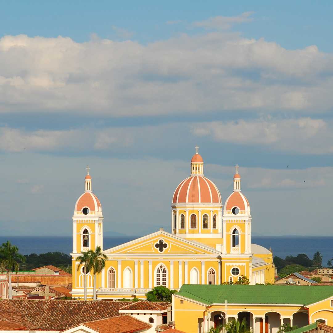 The skyline of Granada, Nicaragua, with its yellow cathedral, rooftops in Spanish colonial style architecture and Lake Nicaragua in the background