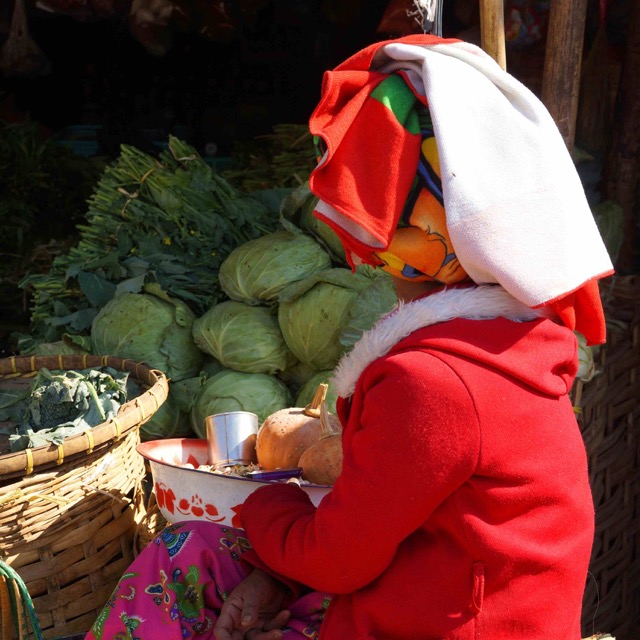 Mujer Shan atiende un puesto de verduras